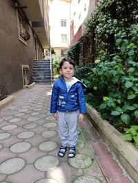 Portrait of boy standing against building