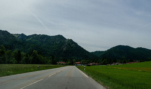 Empty road along landscape and mountains against sky