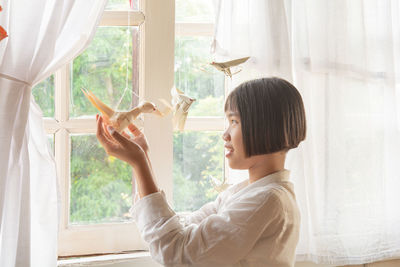 Woman looking through window at home