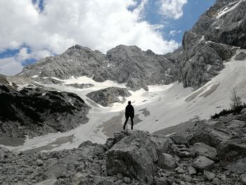 Man walking on snowcapped mountain against sky