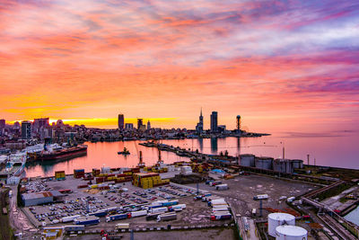 High angle view of harbor by buildings against sky during sunset