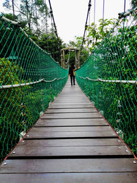 Rear view of woman walking on footbridge