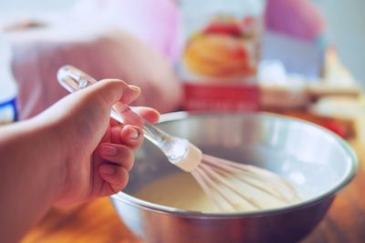 Close-up of hand mixing batter in bowl