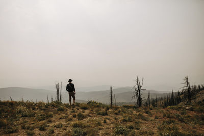 Rear view of man looking at landscape while standing on mountain against sky during sunset