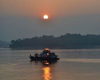 Boat on river against sky during sunrise