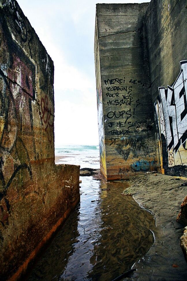 water, built structure, architecture, sea, sky, building exterior, horizon over water, waterfront, day, outdoors, cloud - sky, no people, nature, cloud, wall - building feature, rippled, rock - object, building, reflection, tranquility