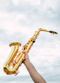 Low angle view of hand playing guitar against sky