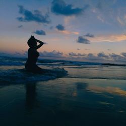 Silhouette man on beach against sky during sunset