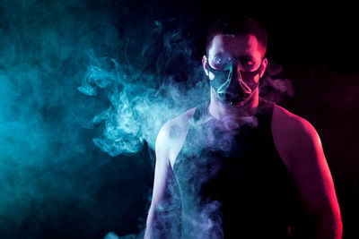 Young man smoking against black background