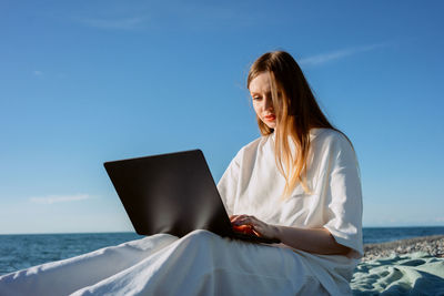 Young woman using laptop at beach