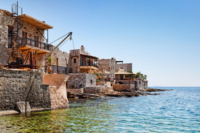 Buildings by sea against clear sky