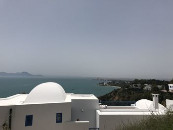 Buildings by sea against clear sky