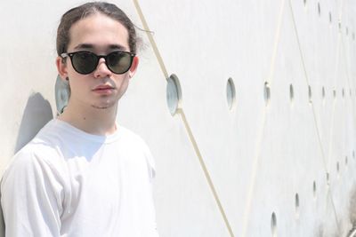 Portrait of young man wearing sunglasses against wall