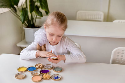 A girl student sits at a desk in the classroom and collects figures / puzzles / small toys 