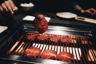 Cropped image of person cooking meat on barbecue grill