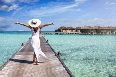 Woman standing by sea against sky