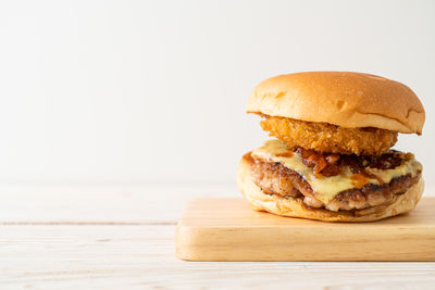 Close-up of burger on cutting board against white background