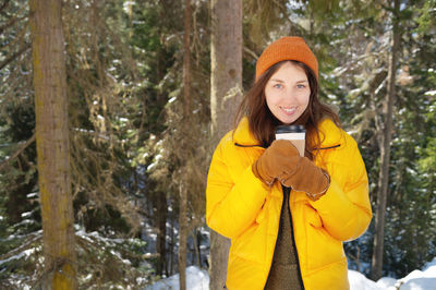 Portrait of smiling young woman standing in forest