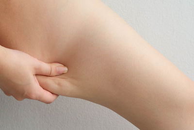 Cropped image of woman pinching thigh