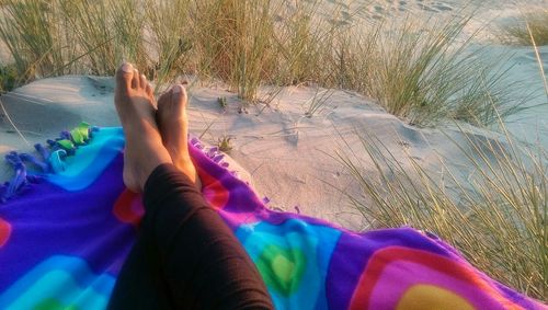 Low section of woman relaxing on sand
