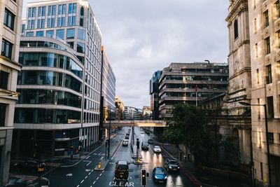 Cars on city street by buildings against sky