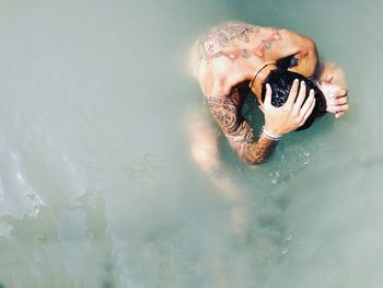 High angle view of shirtless man sitting in sea