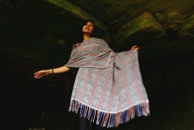 Low angle view of woman wrapped in dupatta while standing in darkroom