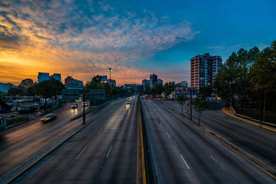 Roads in city against cloudy sky during sunset