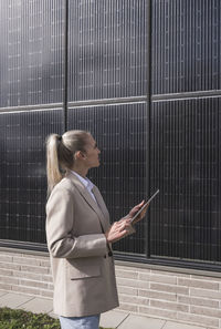 Young businesswoman with tablet pc examining solar panels