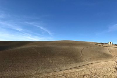 Scenic view of sand dunes against blue sky