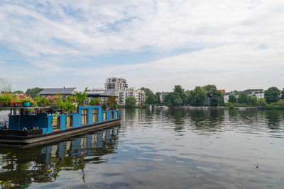 Buildings by river against sky in city