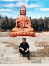 Portrait of young man sitting against sky