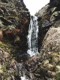 Low angle view of waterfall against sky