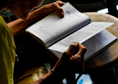 Midsection of senior woman reading book at home