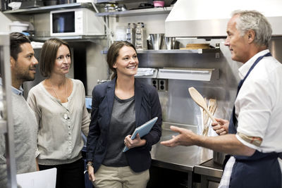 Team of inspectors talking to chef in commercial kitchen