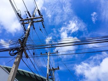 Low angle view of electricity pylon against cloudy sky