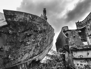 Old abandoned ship on land against sky