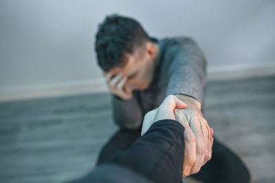 Unrecognizable man with problems receiving help from woman holding her hand