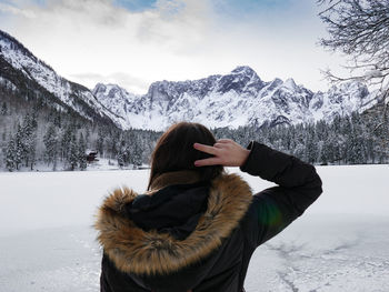 Woman from behind, snowcapped mountain against sky, winter.