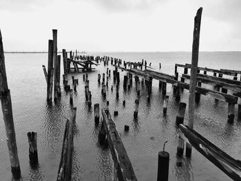 High angle view of wooden posts in sea against sky