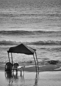Deck chairs on beach against sky