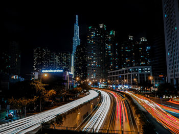 Light trails on road amidst buildings in city at night