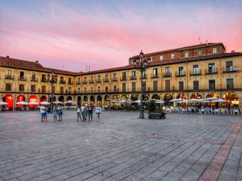 People in city against sky at sunset