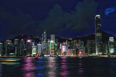 Illuminated modern buildings in city against sky at night