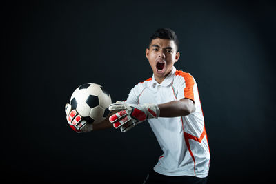 Man playing soccer ball against black background