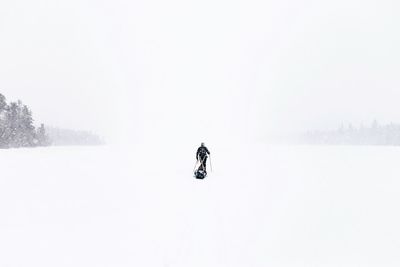 Person skiing in extreme weather on snow covered field against sky