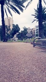 Park bench by building in city against sky