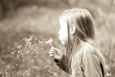 Side view of girl blowing dandelion