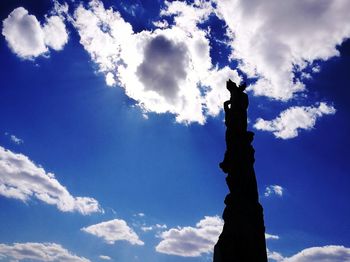 Low angle view of silhouette statue against blue sky