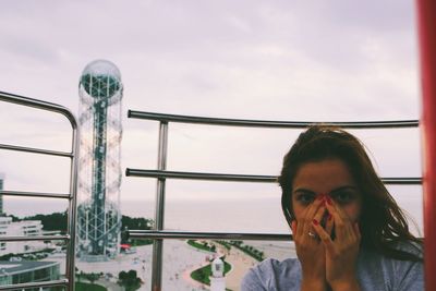 Portrait of woman against railing against sky